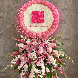Pink and white funeral standing spray with a circular floral tribute above it