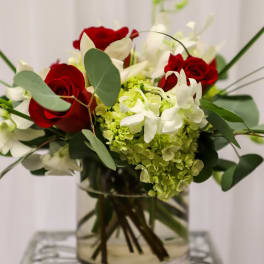 Red roses and white flowers arranged in a clear glass vase