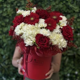Red roses and white hydrangeas in a red hatbox