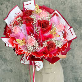 Large bouquet of pink and red roses with butterfly decorations
