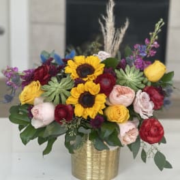 Mixed bouquet with sunflowers and roses in a gold vase