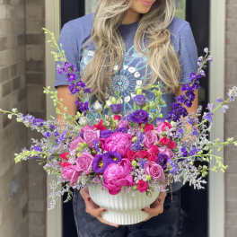 Large pink and purple flower arrangement in a white vase