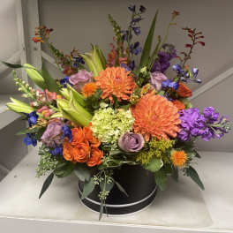 Colorful mixed flower arrangement in a black round box