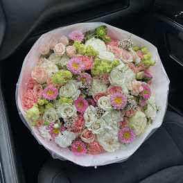 Large bouquet of pink, white, and green flowers wrapped in pale pink mesh