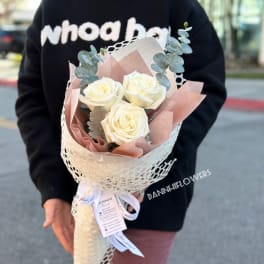 Bouquet of white roses wrapped in pink paper with eucalyptus