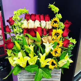 Mixed bouquet of red and cream roses with yellow lilies in a wooden box