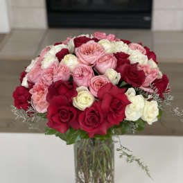 Bouquet of pink, red, and white roses in a clear glass vase