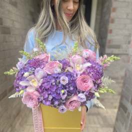 Large pink and purple flower arrangement in a gold box