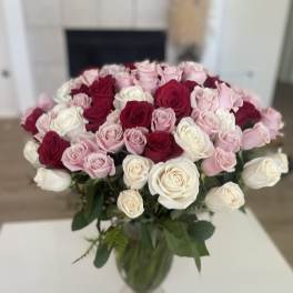 Bouquet of pink, red, and white roses in a clear glass vase