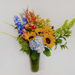 Colorful bouquet with sunflowers, hydrangea, and snapdragons in a glass vase