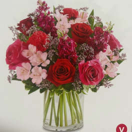 Bouquet of red and pink roses with pale pink flowers in a glass vase