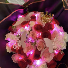 Bouquet of red and pink roses with butterfly decorations and a gold crown