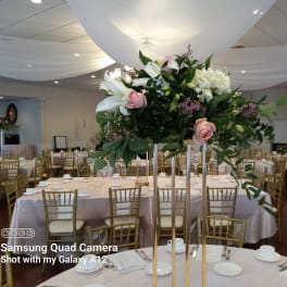 Tall floral centerpiece with white lilies, pink roses, and white hydrangeas