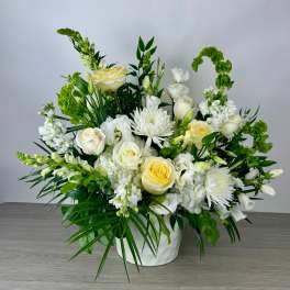 White and pale yellow floral arrangement in a white vase