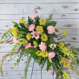 Standing floral spray with pink and yellow flowers on a wire easel