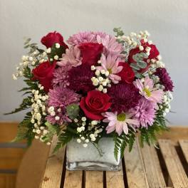 Pink and red flower arrangement in a square glass vase