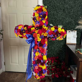 Large floral cross arrangement with red, yellow, purple, and pink flowers
