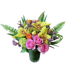 Colorful arrangement of yellow orchids and pink roses in a clear glass vase