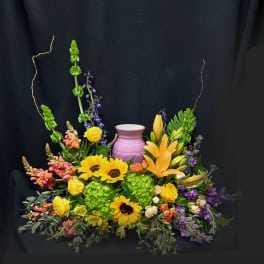 Colorful floral arrangement with sunflowers, lilies, and a purple vase