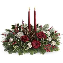 Holiday centerpiece with red candles, roses, and pinecones