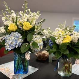 Yellow roses and blue hydrangeas in glass vases