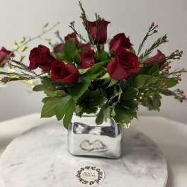 Red rose arrangement in a silver square vase