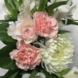 Pink carnations and white lilies with green foliage in a bouquet