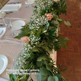 Long floral garland with white baby's breath and pale peach roses on a banquet table