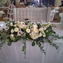 White floral centerpiece with roses and anemones on a table