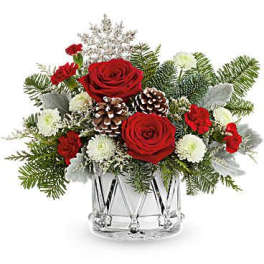 Red roses and white flowers in a clear glass vase with pinecones