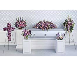 Funeral casket surrounded by pink and purple floral sprays