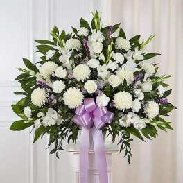 White floral standing spray with a lavender ribbon on a pedestal