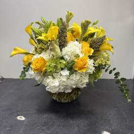Yellow roses and white hydrangeas in a glass bowl vase