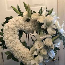 White floral funeral wreath on a stand with lilies and roses