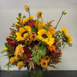 Mixed yellow and red flowers arranged in a clear glass vase