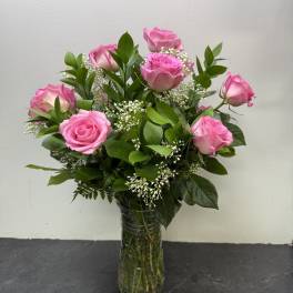 Pink roses arranged in a clear glass vase with white filler flowers