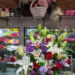 Large bouquet of lilies, roses, and purple flowers in a glass vase