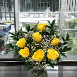 Yellow roses arranged in a clear glass vase with white filler flowers
