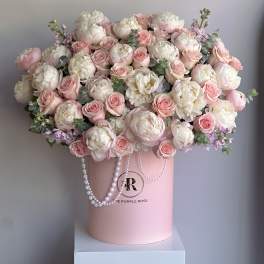 Large arrangement of white peonies and pink roses in a pink hatbox with pearl garlands.