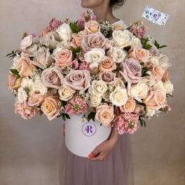 Large hatbox arrangement of cream, blush, and peach roses with pink filler flowers.