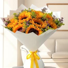 Bouquet of sunflowers wrapped in white paper with a yellow ribbon