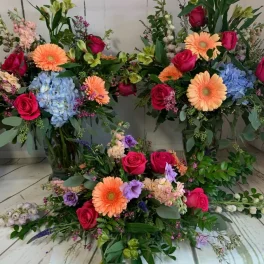 Three colorful floral arrangements with roses, gerbera daisies, and hydrangeas