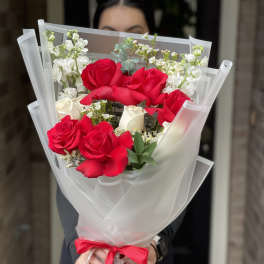 Bouquet of red and white roses wrapped in white paper with a red ribbon