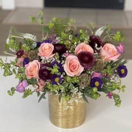 Pink roses and purple mixed flowers in a gold vase