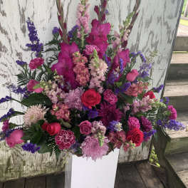 Tall pink and purple floral arrangement in a white vase