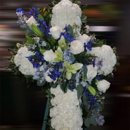 White floral cross on an easel with blue and green accents