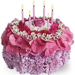 Pink floral cake with lit candles on top