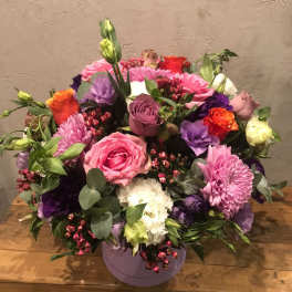 Mixed bouquet of pink, purple, white, and orange flowers in a lavender box