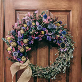 Heart-shaped floral wreath with a burlap bow on a wooden door