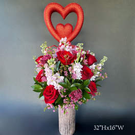Red rose arrangement with a glittery heart topper in a tall vase